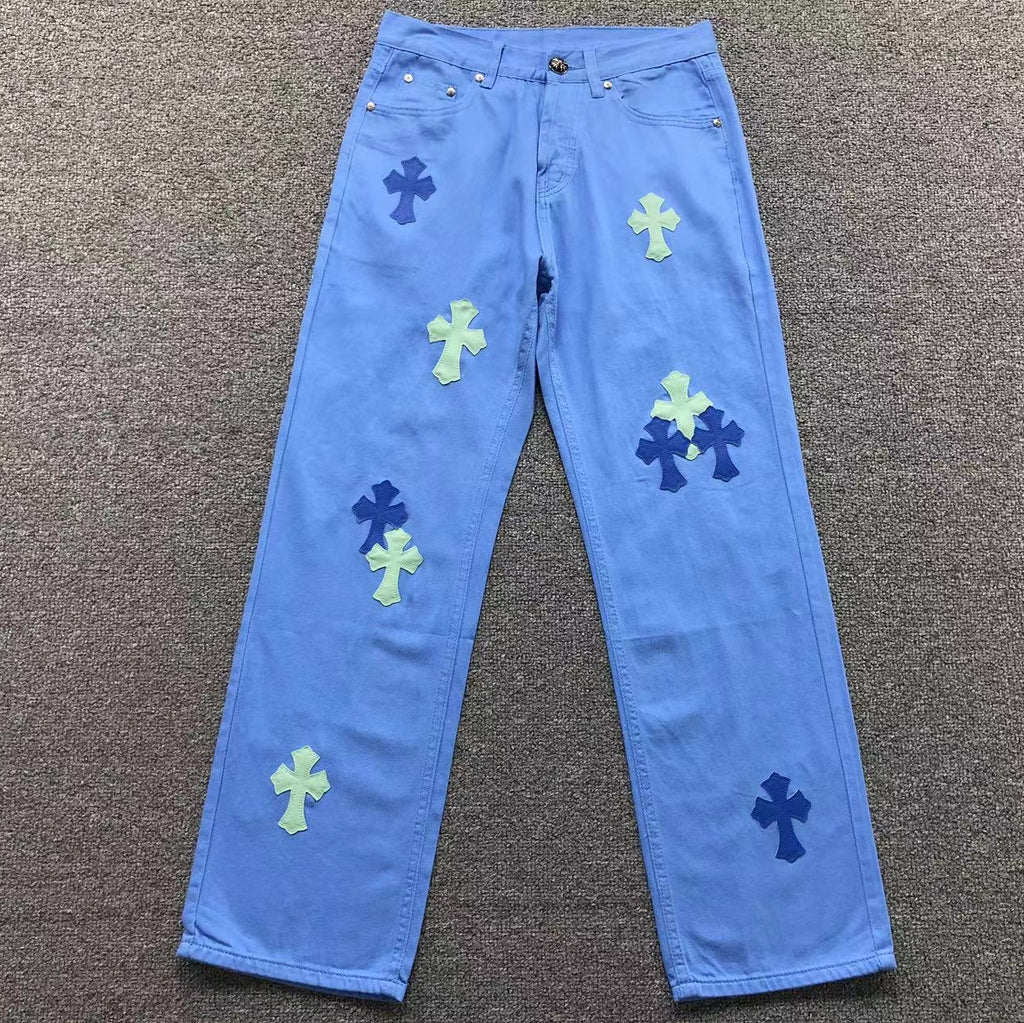 Blue jeans with colorful cross patterns on a gray surface
