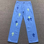 Blue jeans with colorful cross patterns on a gray surface