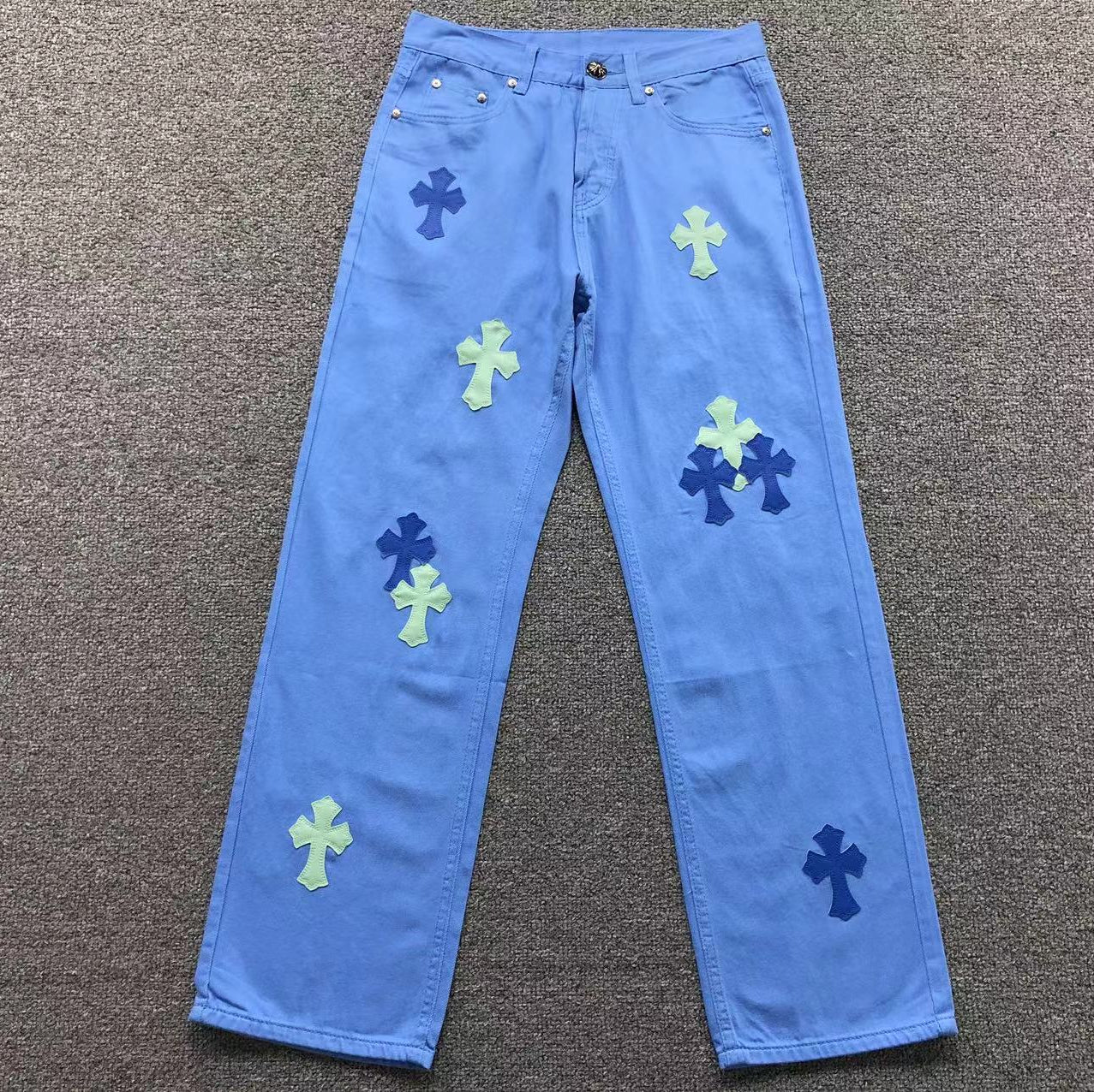 Blue jeans with colorful cross patterns on a gray surface