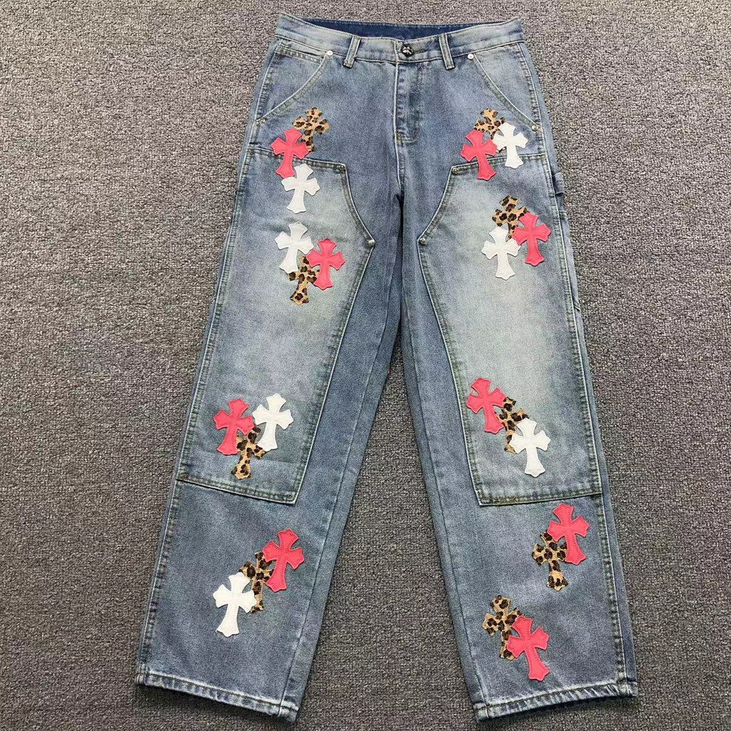 Blue jeans with colorful flower patches on a gray surface