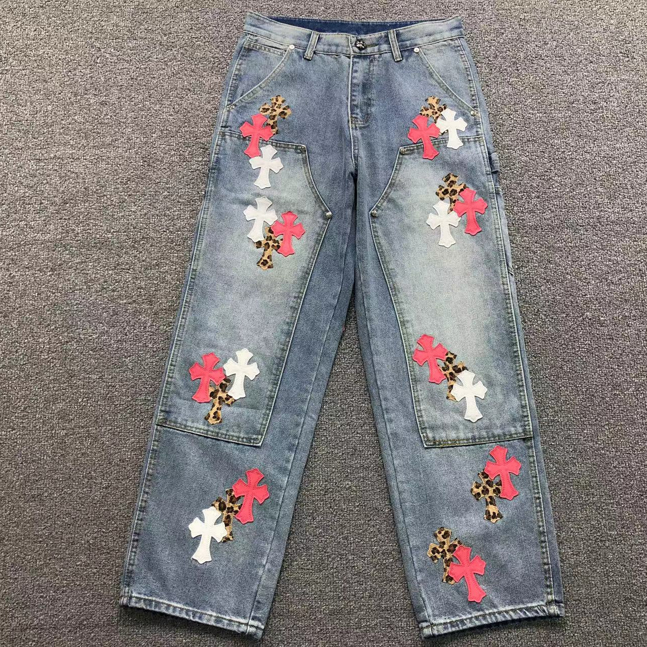 Blue jeans with colorful flower patches on a gray surface